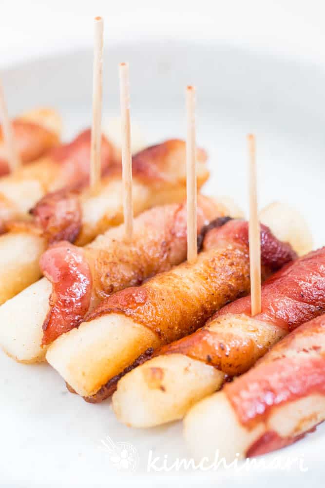 bacon wrapped rice cakes put in a row on a plate