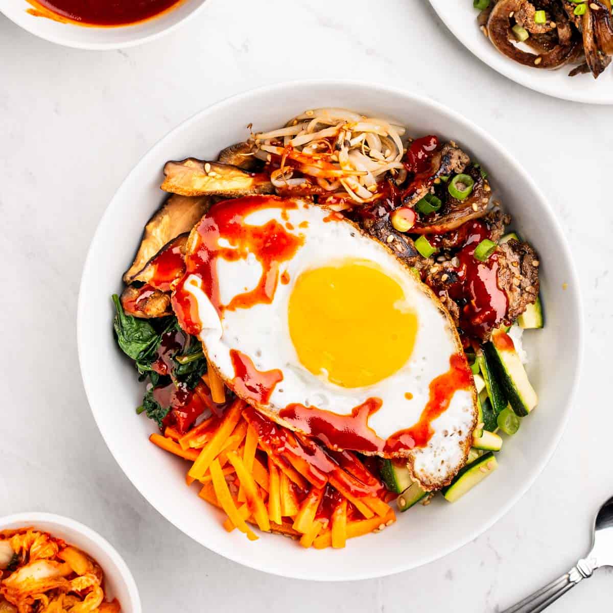 bowl of beef bibimbap with vegetables and sunny side up egg.