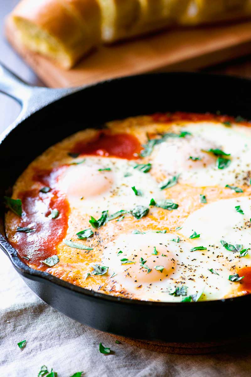 Creamy Italian Baked Eggs! Sunny side up eggs baked on a bed of marinara, milk, and cheese. Serve with garlic bread for that extra dose of Italian flair. | HomemadeHooplah.com