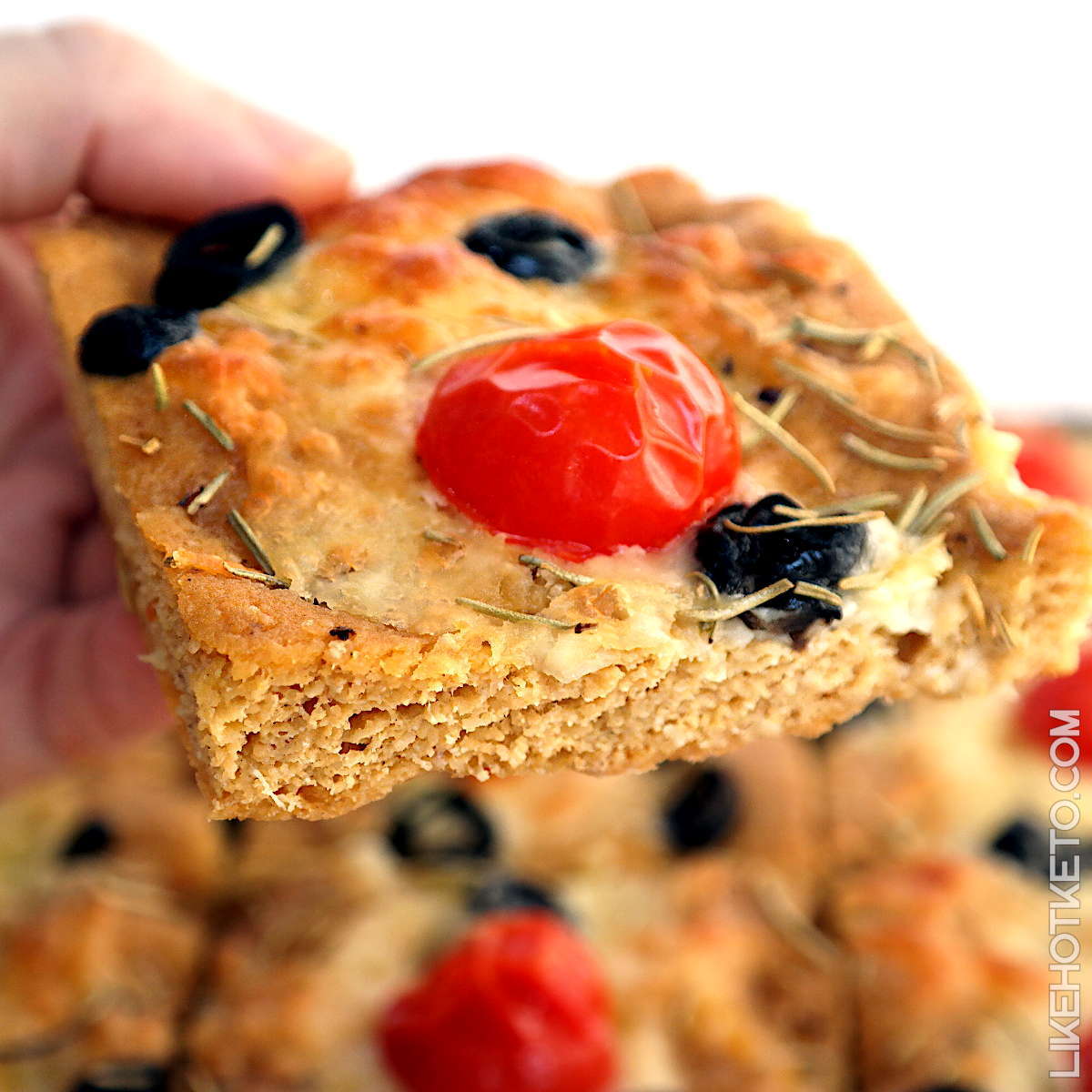 A slice of keto Italian focaccia bread, topped with tomato, mozzarella and black olive.