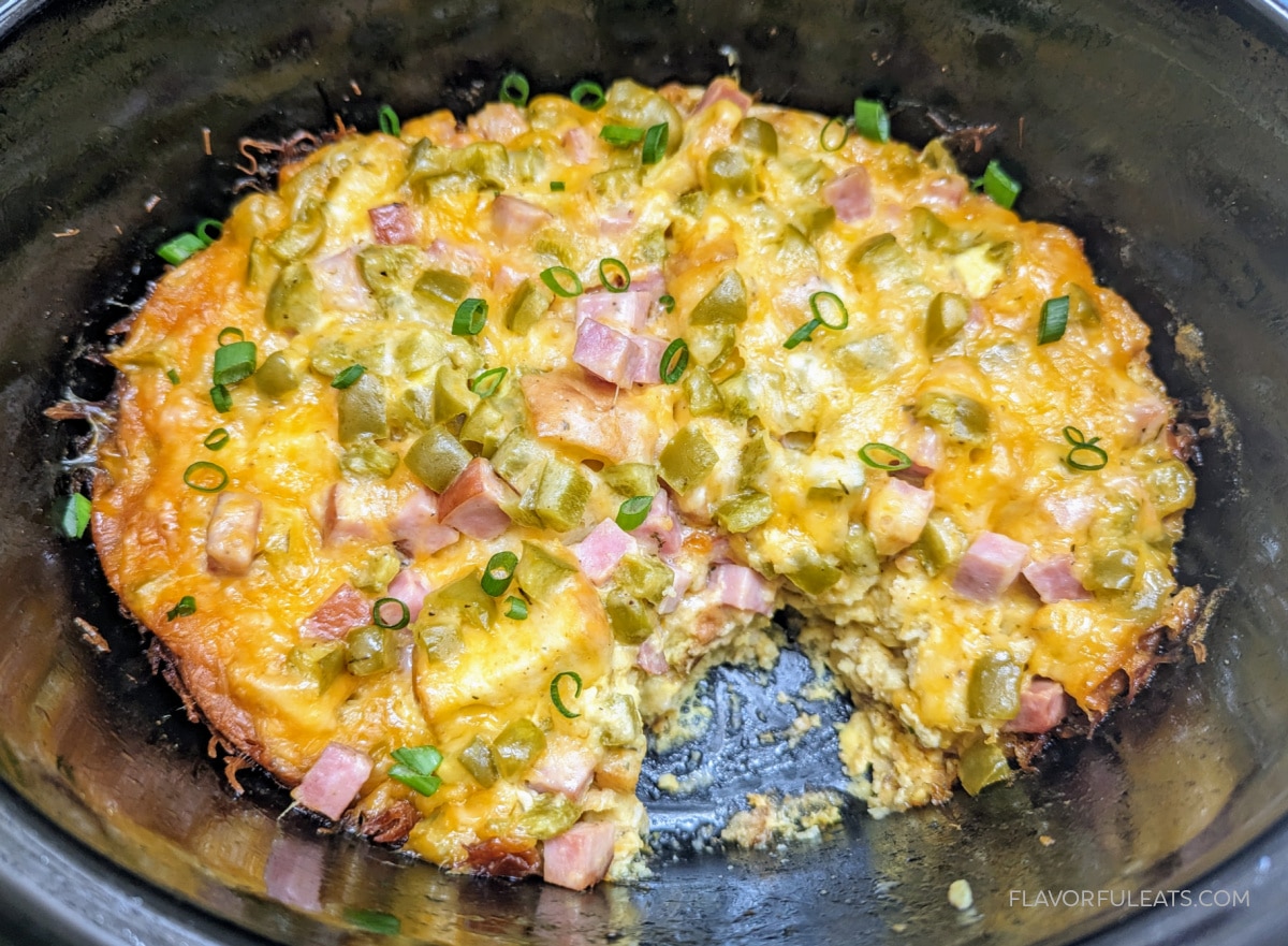 Slow Cooker Denver Omelet Breakfast Casserole in the slow cooker with a serving removed to show the inside.