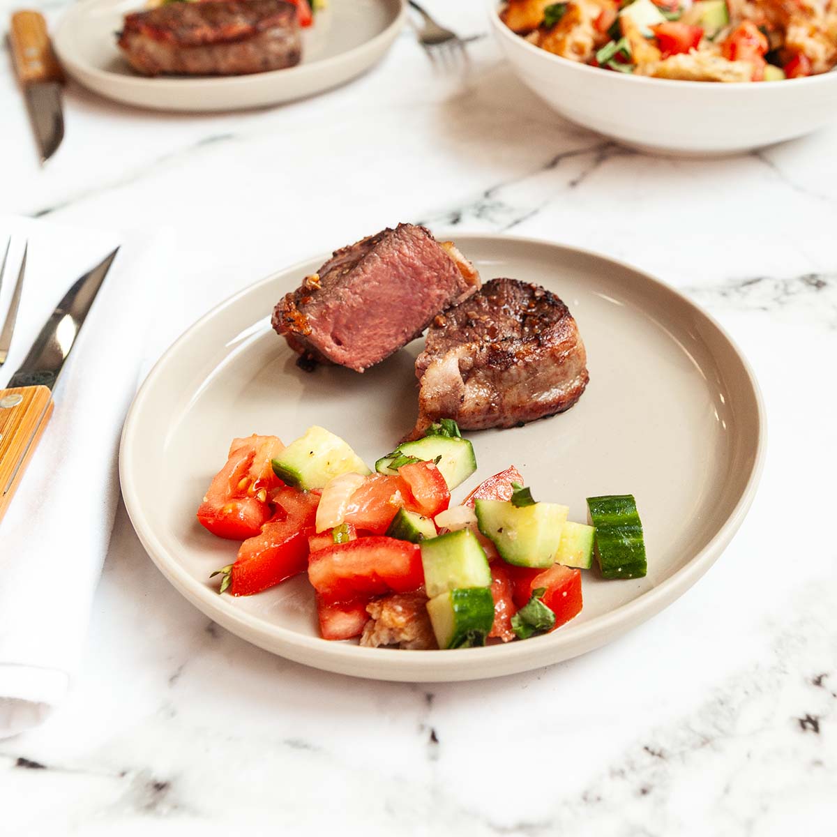 A steak cut in half on a plate with some salad.