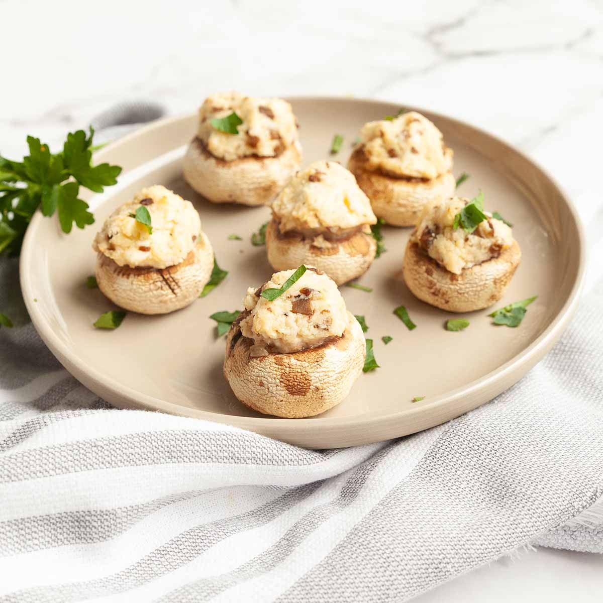 Six grilled stuffed mushrooms on a plate.