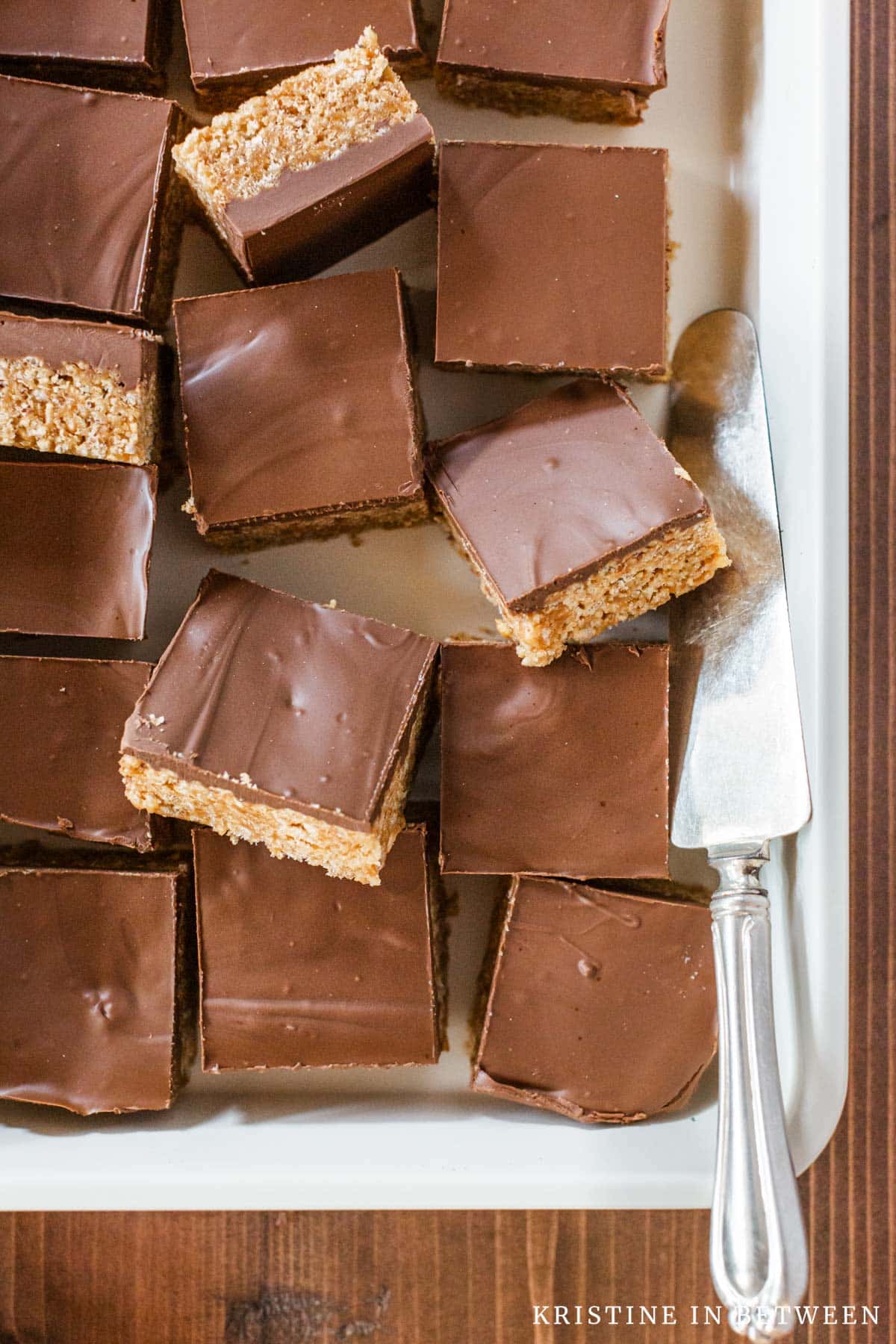 Sliced scotcheroo bars in a baking pan with an antique spatula.
