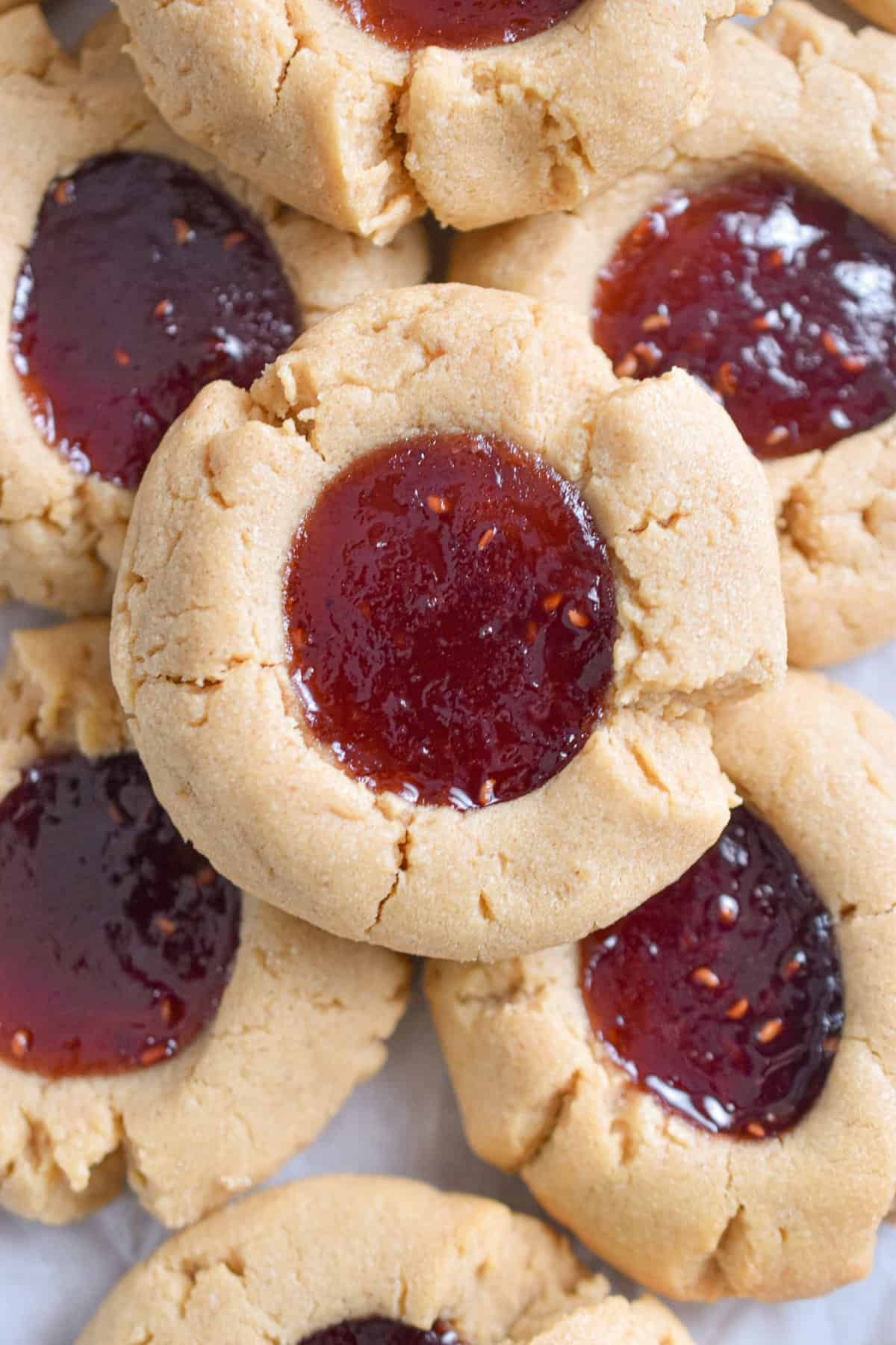 A pile of peanut butter and jam thumbprint cookies is shown.