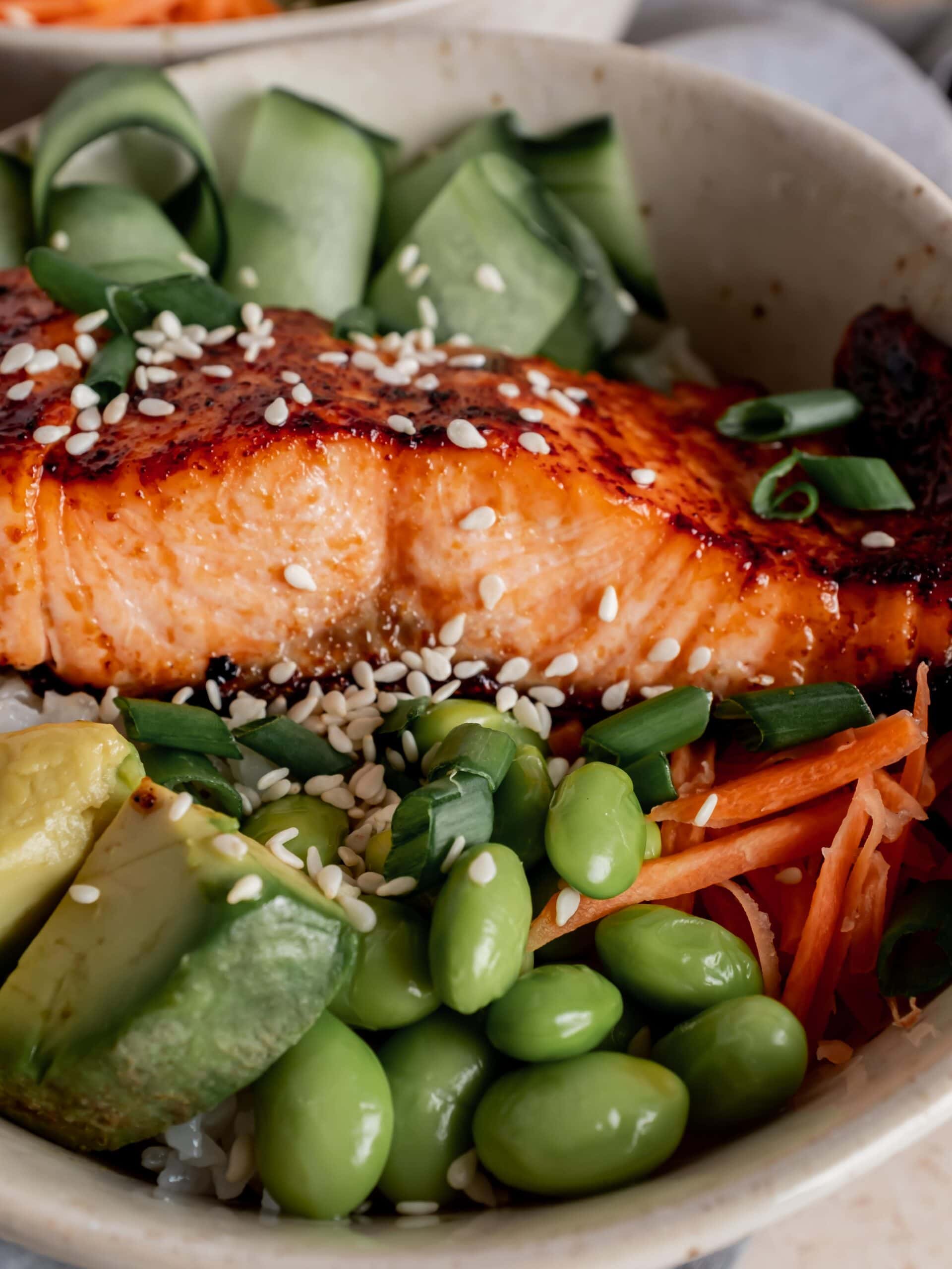 broiled salmon over sushi rice with edamame, avocado, carrots and cucumber