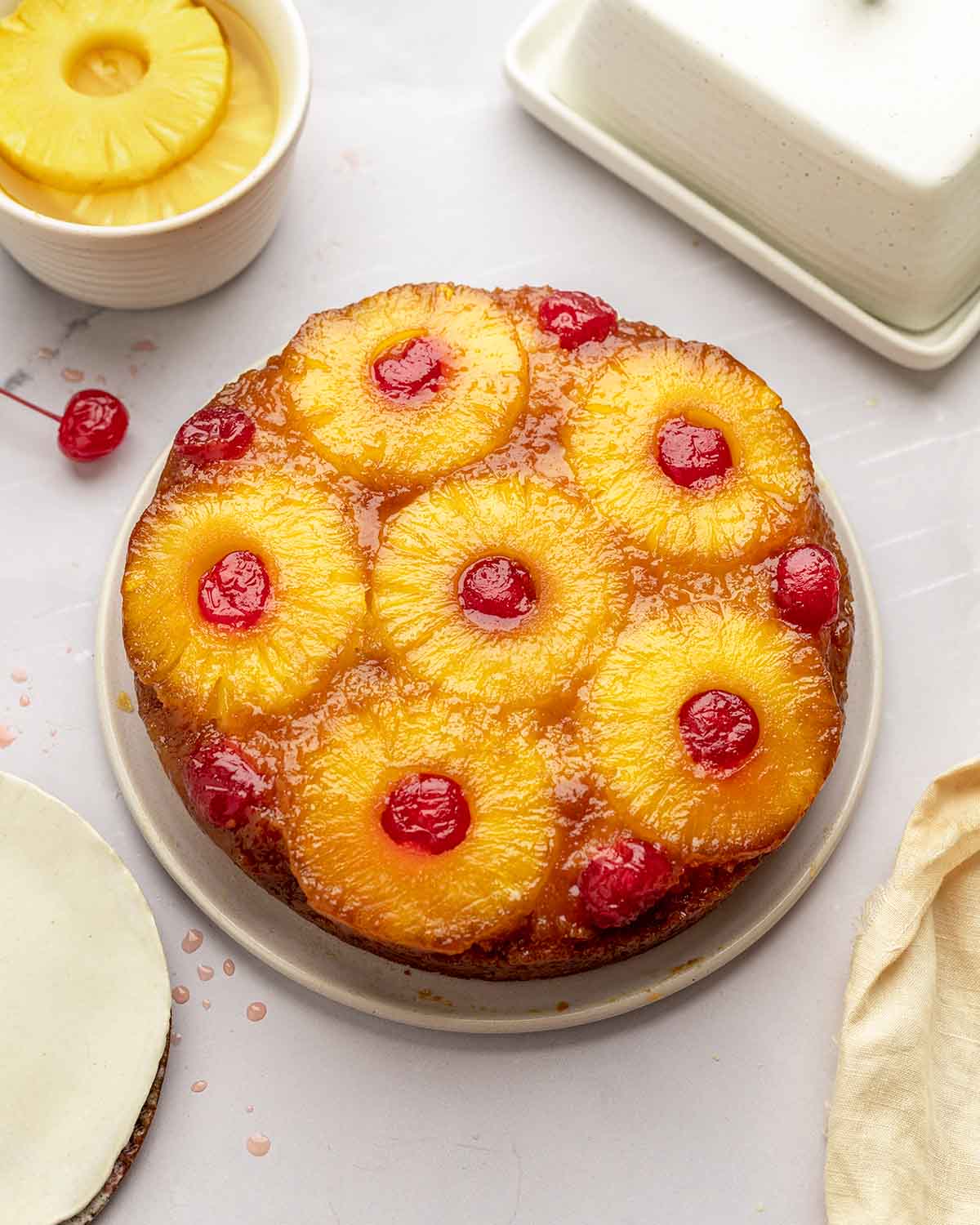 Classic pineapple upside down cake on plate with very glossy topping.