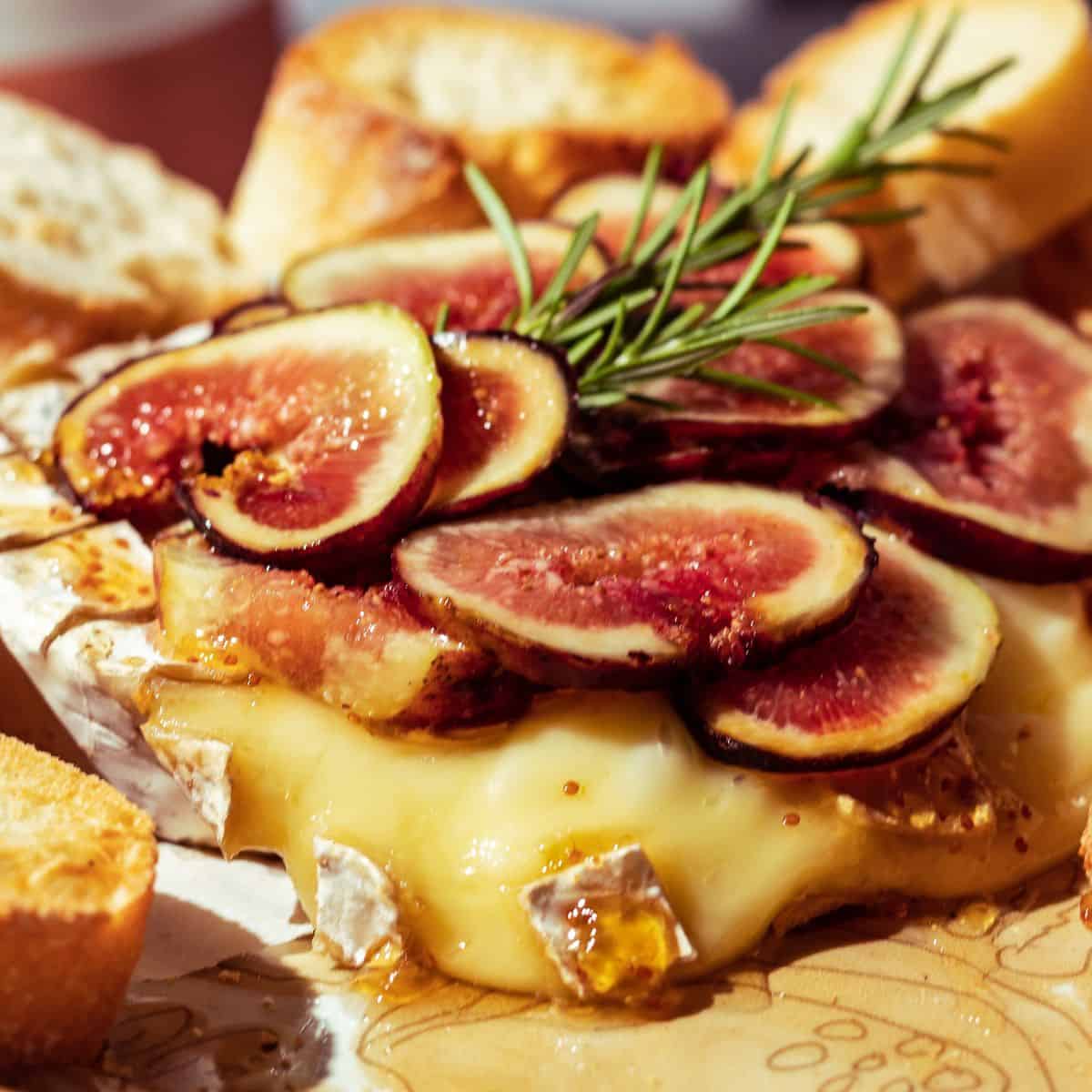 Melted brie cheese with fresh figs and bread slices.