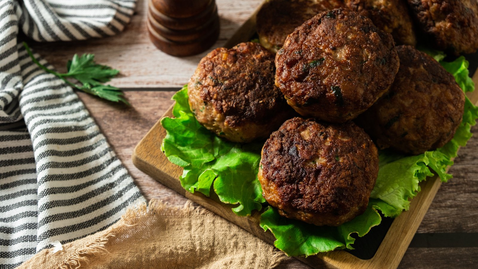 A pile of German frikadellen meatball patties on a bed of lettuce.