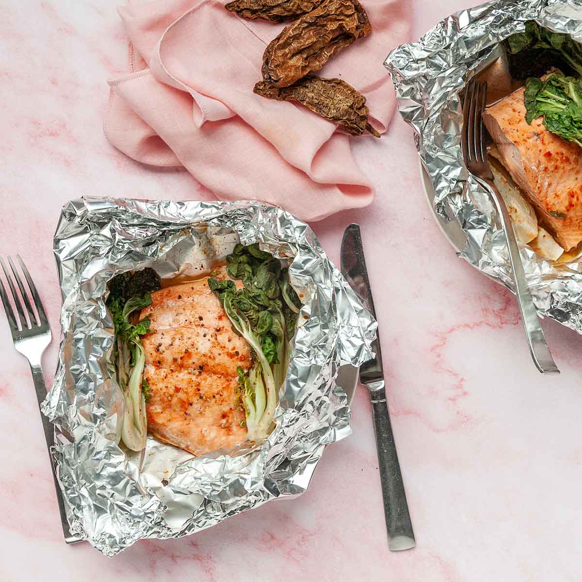 Two foil packets with salmon and bok choy.