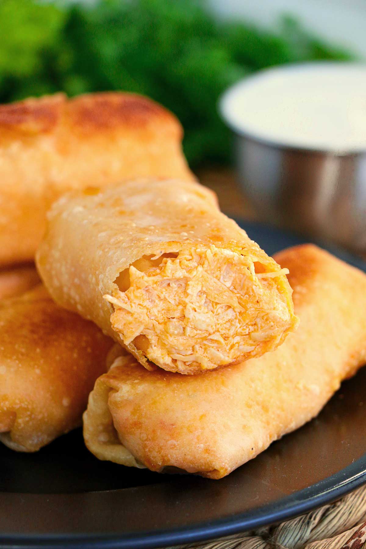 Prepared buffalo chicken egg rolls stacked with one facing the camera that