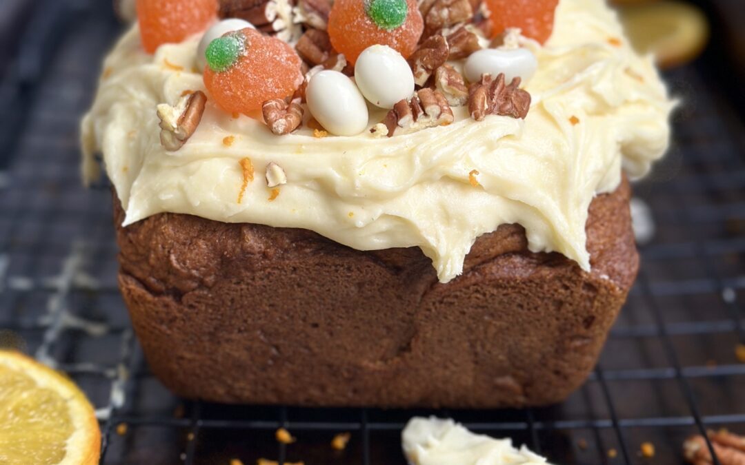 Pumpkin bread loaf topped with orange cream cheese frosting.