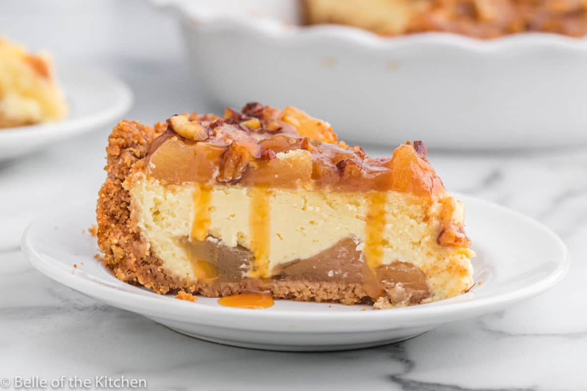 Caramel apple cheesecake topped with apple slices and caramel sauce.