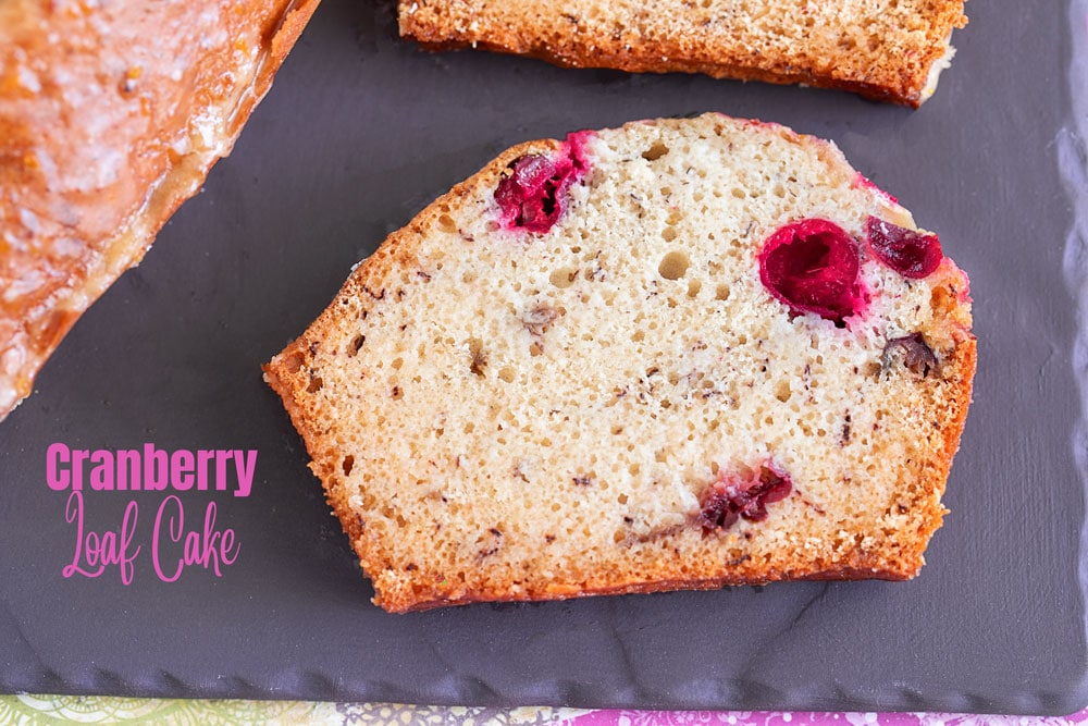 Cranberry loaf cake sliced on a board.