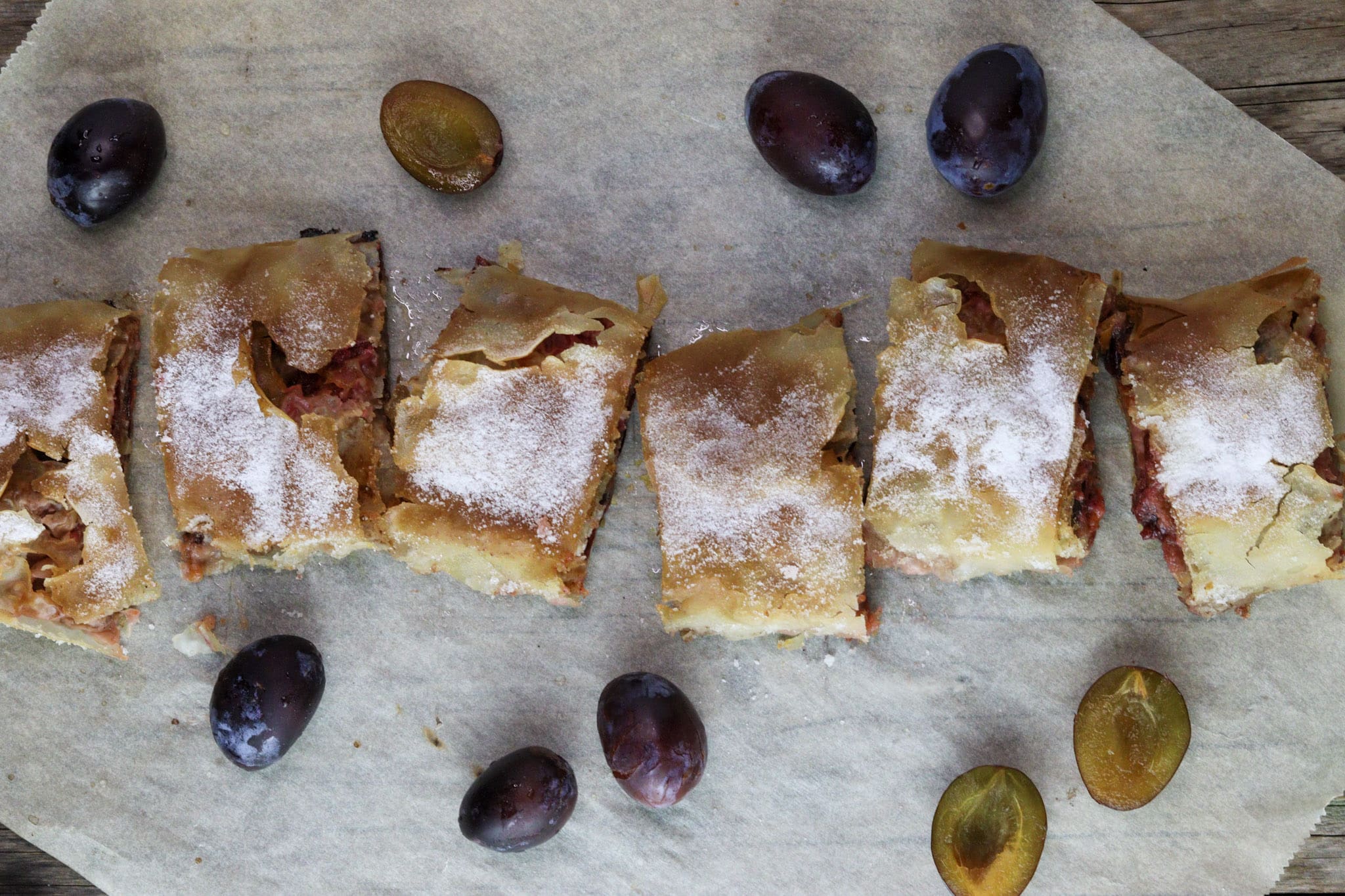 Sliced plum strudel dusted with powdered sugar.