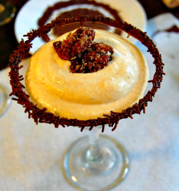 Glasses of pumpkin mousse topped with candied pecans and chocolate.